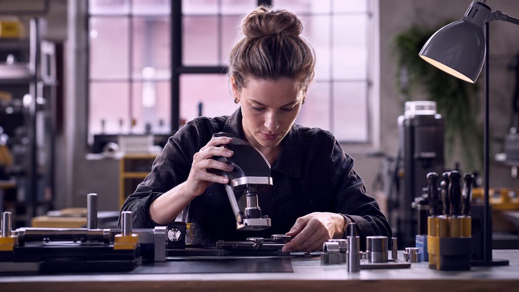 High-performance new tool poised above a carefully maintained, well-organised engineer''s bench and test pieces